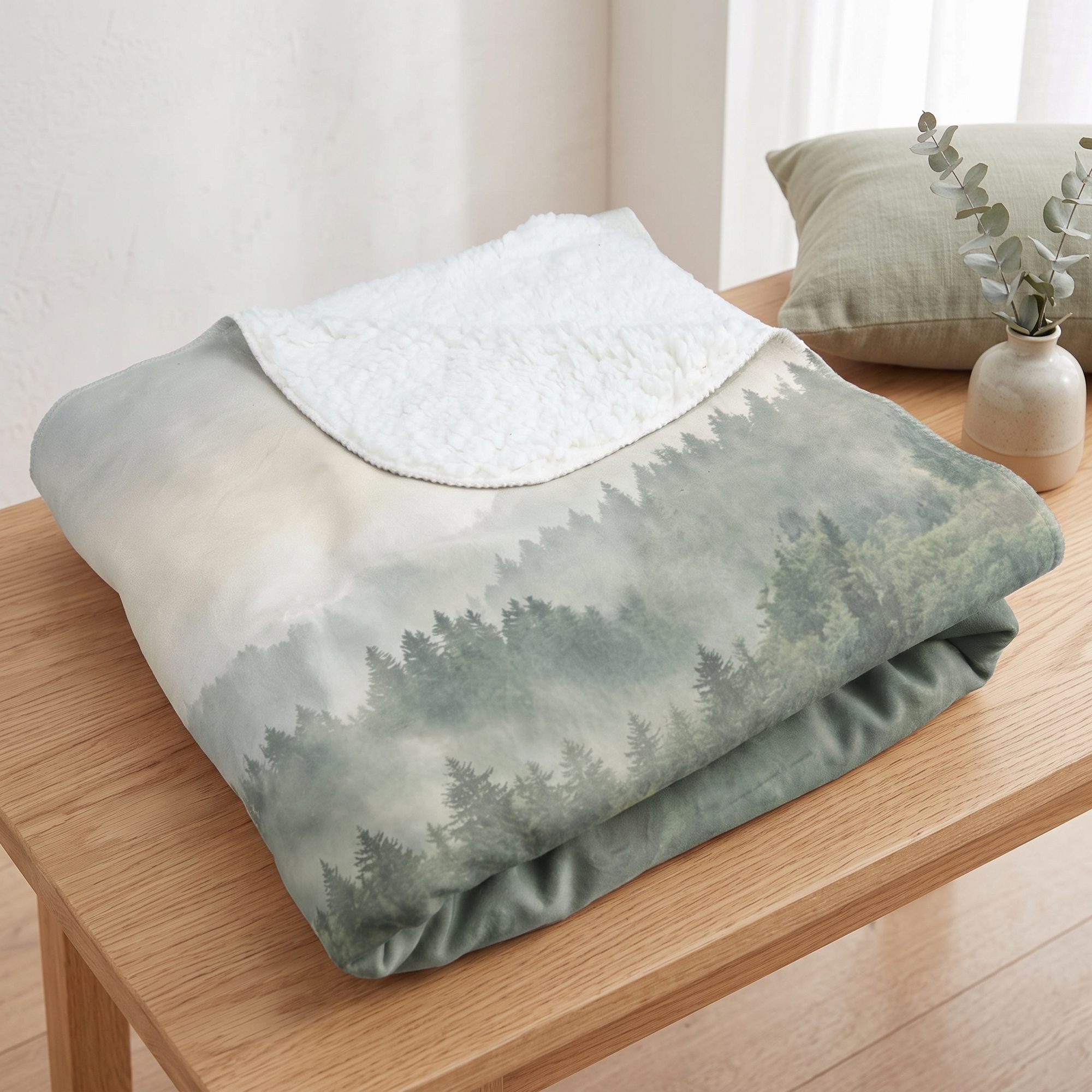 Gefaltete Kuscheldecke mit Waldmotiv und weißer Sherpa-Rückseite